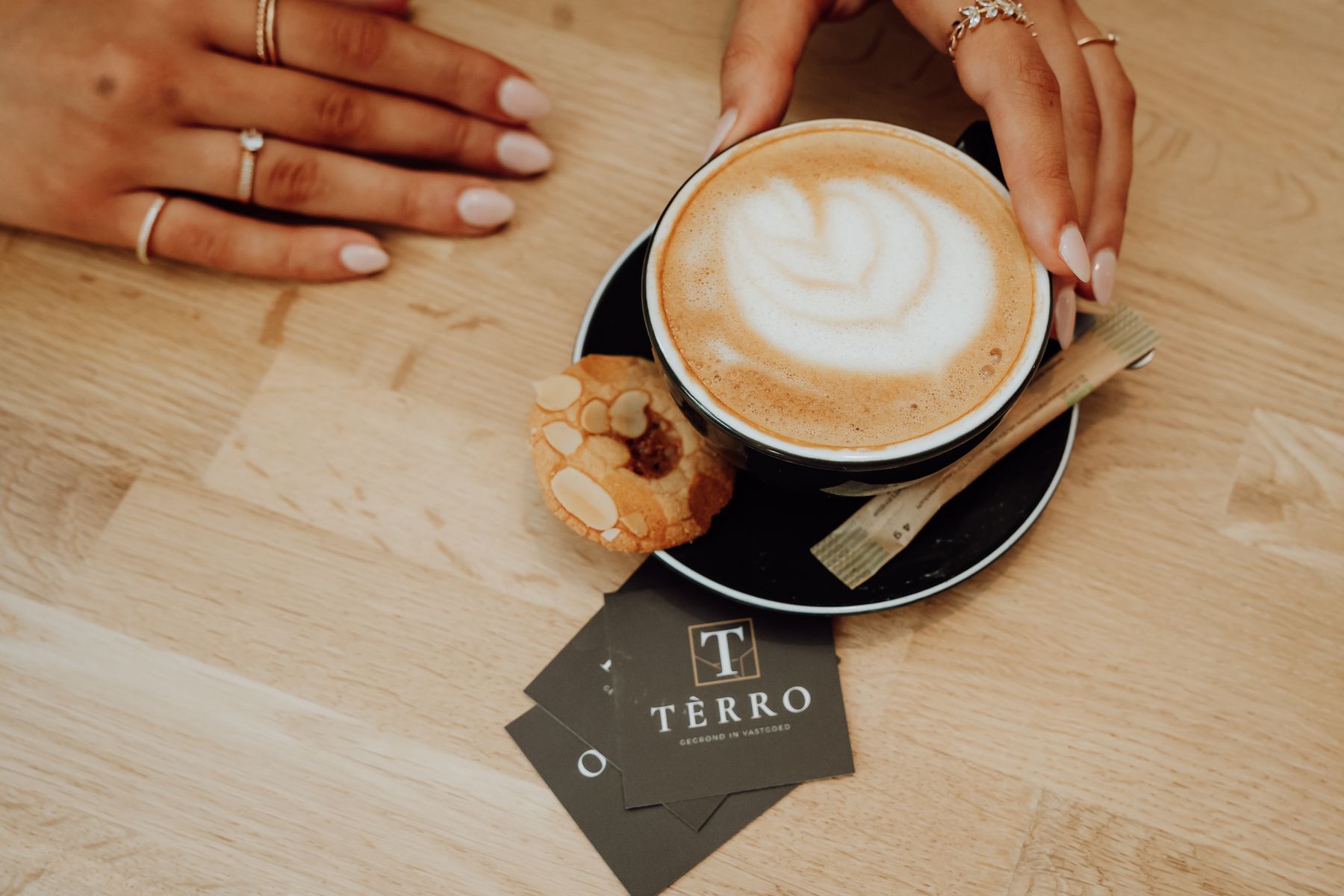 Cappuccino met TÈRRO-visitekaartjes op een houten tafel