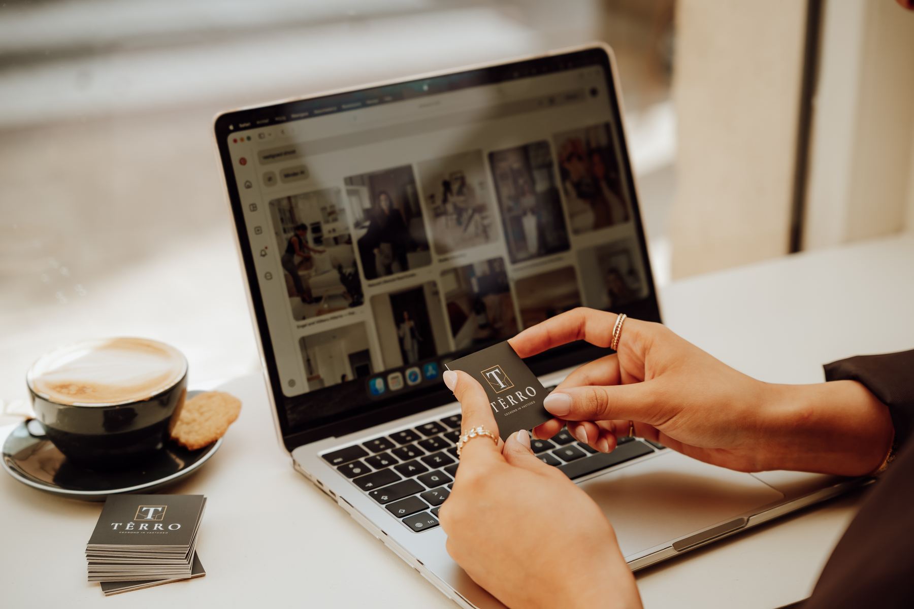 Laptop met woningfoto's, een TÈRRO-visitekaartje en een kop koffie